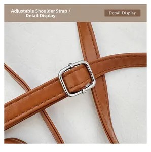 Macro detail of brown leather adjustable shoulder strap with silver buckle and stitching