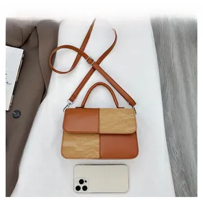 Top view of brown and beige patchwork crossbody bag next to a smartphone for size reference