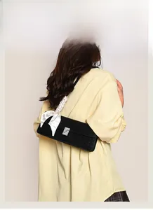 Detail of black embossed leather baguette bag with silver buckle and silk scarf strap