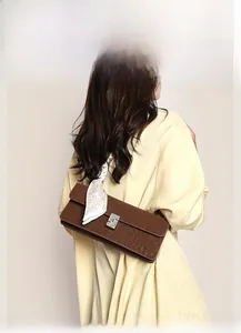 Detail of brown baguette bag with silver rhinestone buckle and polka dot silk scarf