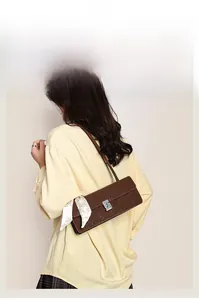 Brown leather baguette bag with a white floral scarf handle detail on a beige shirt