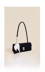 Close-up of black leather baguette bag featuring rhinestone buckle and silk scarf handle