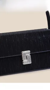 Detail of black baguette bag with vertical texture and silver rhinestone buckle