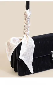 Detail of black pleated shoulder bag with sparkling rhinestone buckle and scarf handle