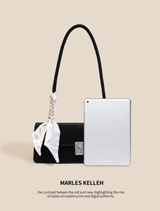 Close-up of black textured baguette bag with rhinestone buckle and decorative silk scarf