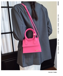 Mini sac à main fuchsia porté en bandoulière sur un modèle avec blazer gris