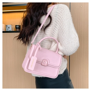 Detail showing pink leather handbag with top handle and detachable shoulder strap on model