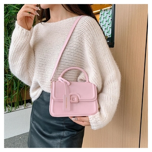 Pink minimalist leather handbag detail showing the structured handle and fashion tag