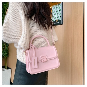 Close-up of pink fashion handbag with brand tag detail and adjustable shoulder strap