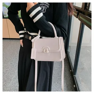 Detail of minimalist beige handbag showing square buckle and branded leather tag
