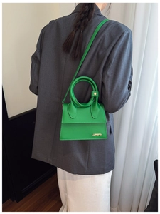 Détail d'un sac à main vert vif avec poignée ronde porté sur un blazer gris