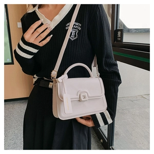 Detail of a beige leather crossbody bag with a square buckle and fashion logo tag