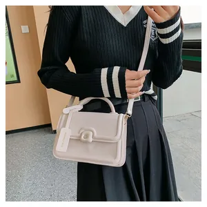 Close-up of cream PU leather crossbody bag with square buckle and fashion tag