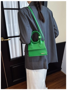 Mini sac à bandoulière vert avec poignée ronde et logo en métal sur fond minimaliste