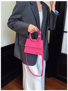 Detail of trendy magenta trapezoid handbag with oversized round handle and gold metal logo
