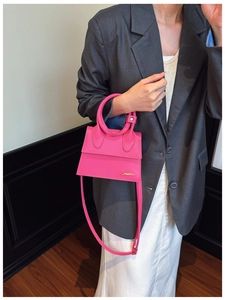 Vue détaillée d'un mini sac à main rose vif avec poignée ronde et logo en métal doré