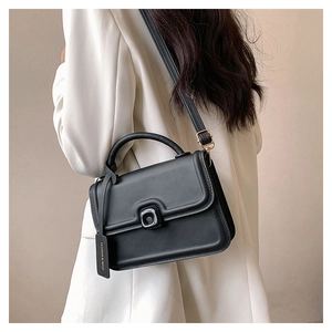 Side view of a black square crossbody bag worn with a white blazer for a chic look