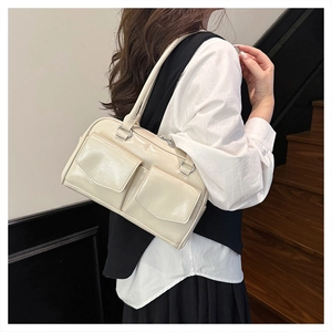 Detail einer cremefarbenen Schultertasche mit aufgesetzten Taschen und glattem Kunstleder