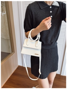 Détail du mini sac blanc en cuir avec logo doré, poignée ronde et bandoulière chic