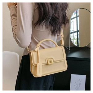 Detail of yellow leather crossbody bag with brand tag and adjustable strap on a model