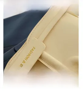Detail view of smooth light yellow leather stitching and Fashion & Bags engraved buckle