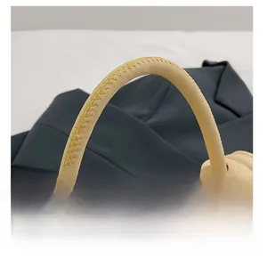 Detail view of the beige handbag handle featuring contrast yellow stitching on leather