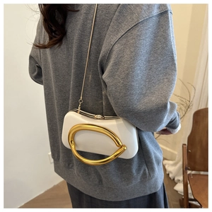 Détail d'une pochette de soirée blanche avec poignée sculpturale dorée et bandoulière