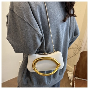 Pochette de soirée blanche avec anneau doré et chaîne, portée par un mannequin de mode