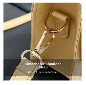 Close-up of golden metal hook on a cream leather bag with removable shoulder strap