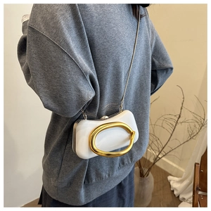 Détail de la pochette rigide blanche avec pièce en métal doré et bandoulière chaîne