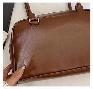 Nahaufnahme der dunkelbraunen Boston-Tasche aus geprägtem Leder mit silbernen Ring-Elementen