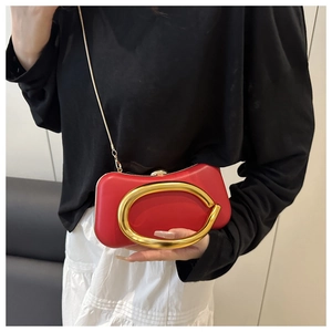 Détail de la pochette de soirée en cuir rouge avec poignée dorée ovale et chaîne dorée