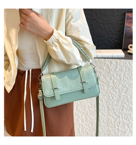 Detail of mint green crossbody bag featuring woven texture flap and silver metal buckle