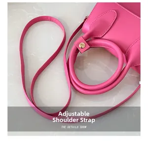 Détail du sac en cuir fuchsia montrant la poignée ronde et la bandoulière réglable