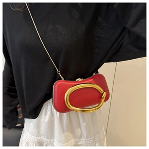 Pochette de soirée rouge avec poignée dorée portée par un mannequin en noir et blanc