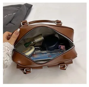 Makroansicht des großen Innenraums der braunen Ledertasche mit Alltagsgegenständen