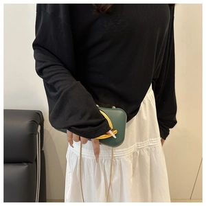 Détail de la pochette de soirée vert foncé avec boucle dorée ronde et fine chaîne
