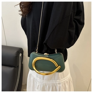 Détail de la pochette rigide vert foncé avec boucle dorée et bandoulière chaîne