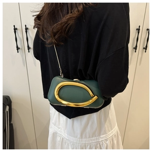 Détail de la pochette vert foncé avec un anneau métallique doré en C et une bandoulière