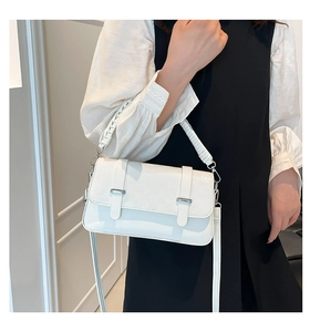 Close-up of white crocodile texture leather handbag with woven handle and silver metal buckle