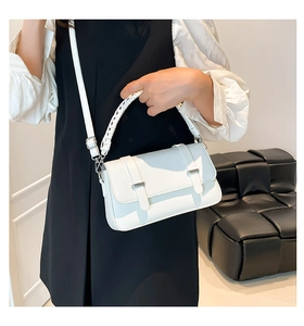 Detail view of white crocodile embossed satchel with woven handle and silver buckles
