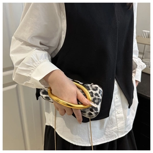 Close-up of leopard print evening bag featuring a large gold ring handle and chain strap
