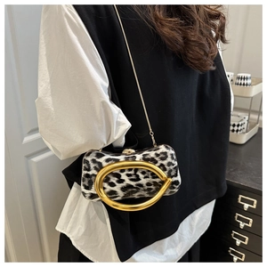 Detail of leopard print crossbody bag featuring a large gold metal handle and chain strap