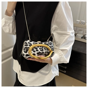 Detail view of leopard print clutch bag featuring a gold C-handle and metal chain strap