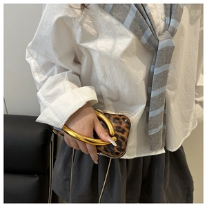 Detail showing leopard print clutch with gold metal handle and chain strap