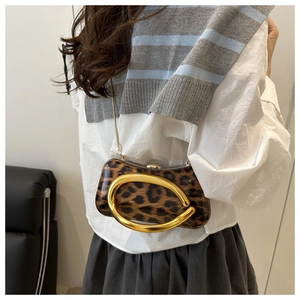 Detail of leopard print crossbody bag with large gold ring handle shown on model