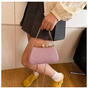 Close-up of pink lace evening bag with pearl clasp and elegant gold chain strap