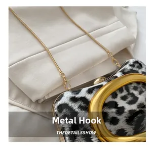 Detail of leopard print evening bag with glossy finish and gold round ring hardware hooks