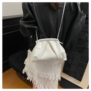 Detailed close-up of the white woven texture and elegant pleated cloud bag design