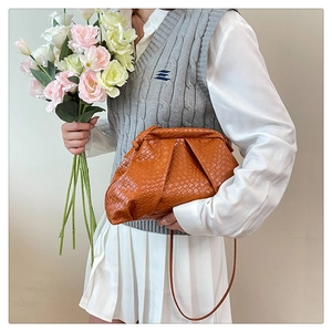 Detail of a brown woven cloud bag with stylish texture and matching thin shoulder strap
